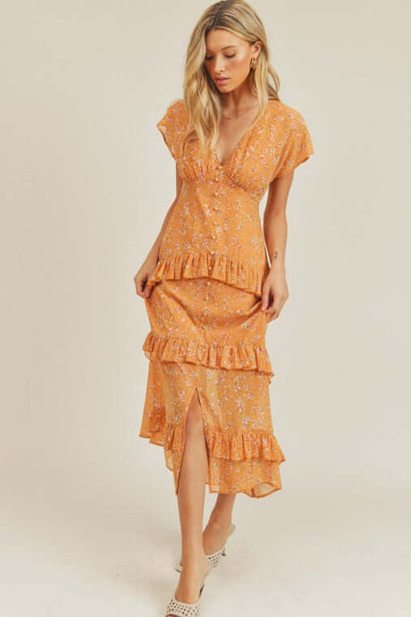 Woman wearing orange floral midi dress in garden setting