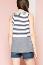 Woman wearing THML black and white stripped tank top with green embroidered neckline with orange ball details back.