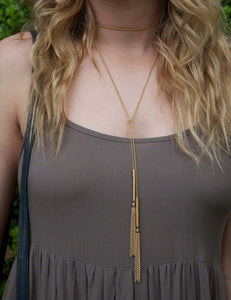 Woman wearing boho gold chain and tassel wrap around necklace.