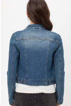 Woman wearing long sleeve button up front closure waist length blue jean denim jacket back.