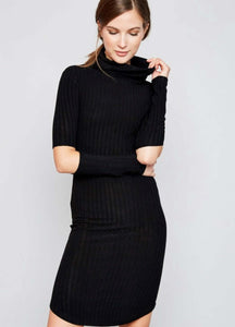 Woman in black knee length ribbed dress with cut out style at elbows and crowl neckline front.