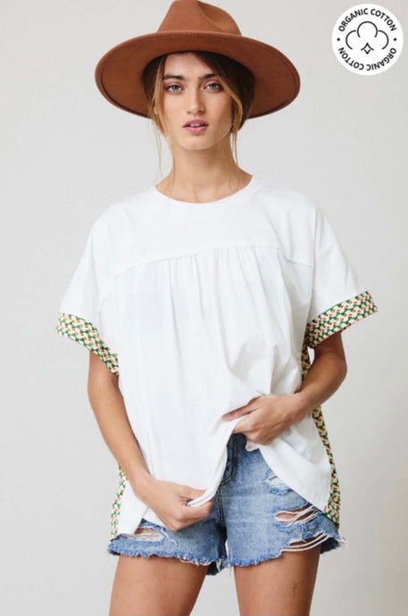 Woman wearing certified organic cotton oversize white top with color block Aztec green and white colorful design front.