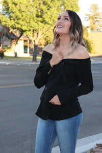 woman in Solid black tuxedo style off the shoulder long sleeve top.