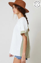 Woman wearing certified organic cotton oversize white top with color block Aztec green and white colorful design side.