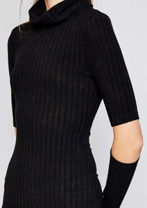 Woman in black knee length ribbed dress with cut out style at elbows and crowl neckline side.