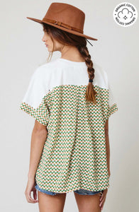 Woman wearing certified organic cotton oversize white top with color block Aztec green and white colorful design back.