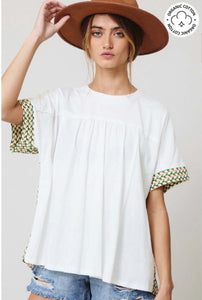 Woman wearing certified organic cotton oversize white top with color block Aztec green and white colorful design front.