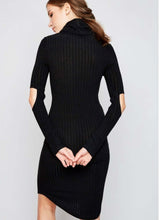 Woman in black knee length ribbed dress with cut out style at elbows and crowl neckline back.