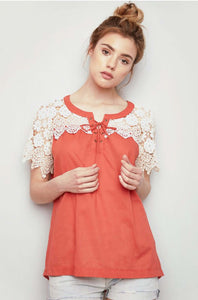 Women's orange lightweight top with lace up front and cream lace sleeves front.
